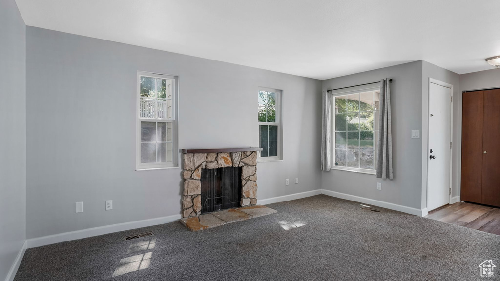 Unfurnished living room with plenty of natural light, a fireplace, and carpet flooring