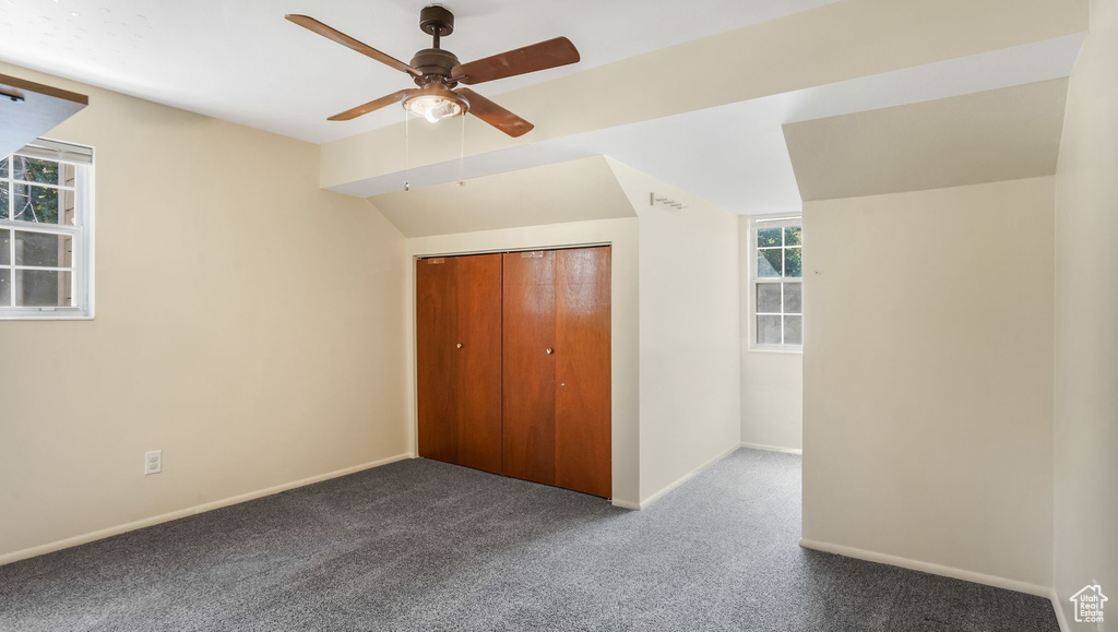 Unfurnished bedroom with carpet floors, baseboards, a closet, vaulted ceiling, and ceiling fan