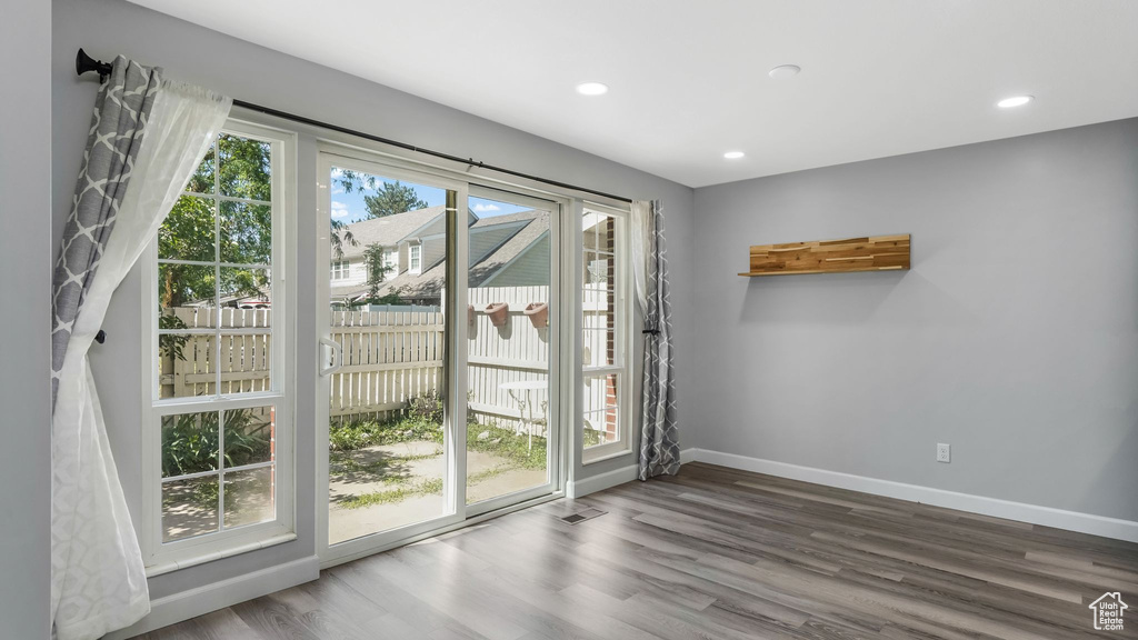 Doorway with wood finished floors, baseboards, and recessed lighting
