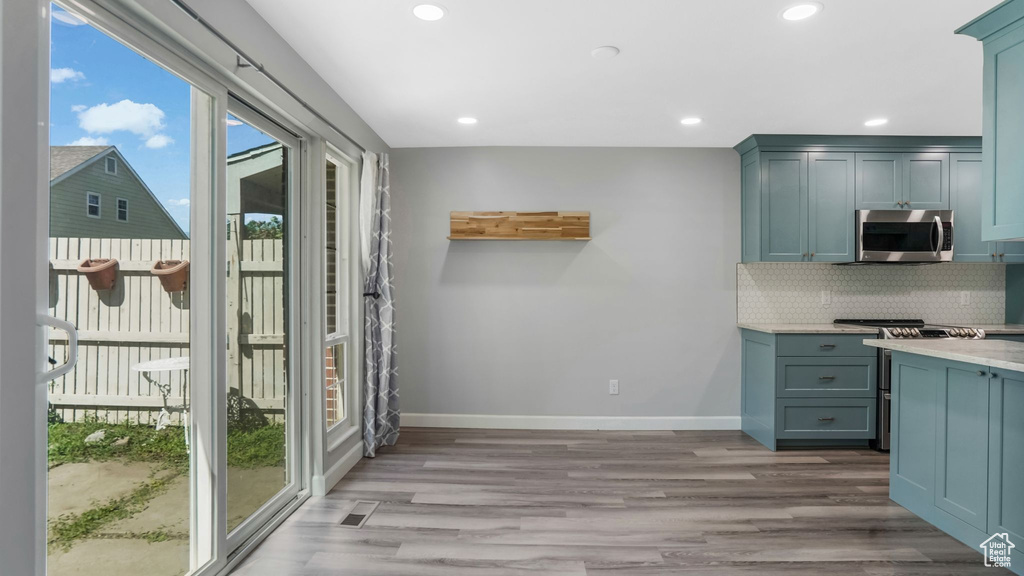 Kitchen featuring stainless steel microwave, baseboards, wood finished floors, tasteful backsplash, and recessed lighting