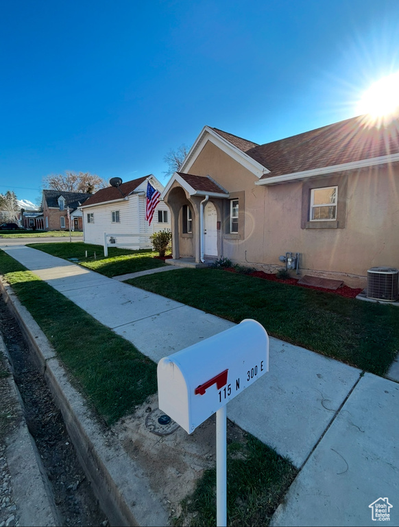 Single story home with stucco siding, a front yard, roof with shingles, and cooling unit