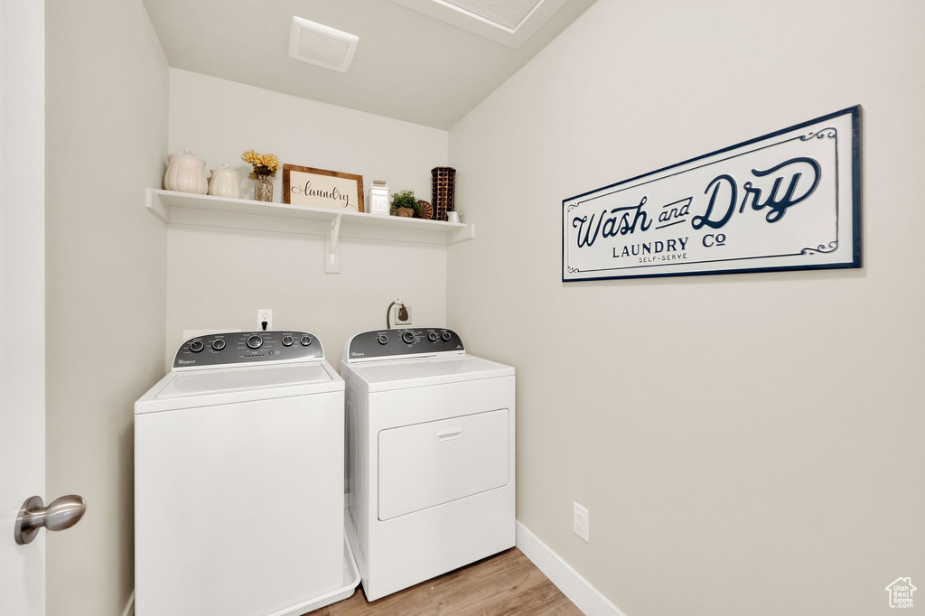 Laundry area featuring washer and dryer, light wood-style floors, and baseboards
