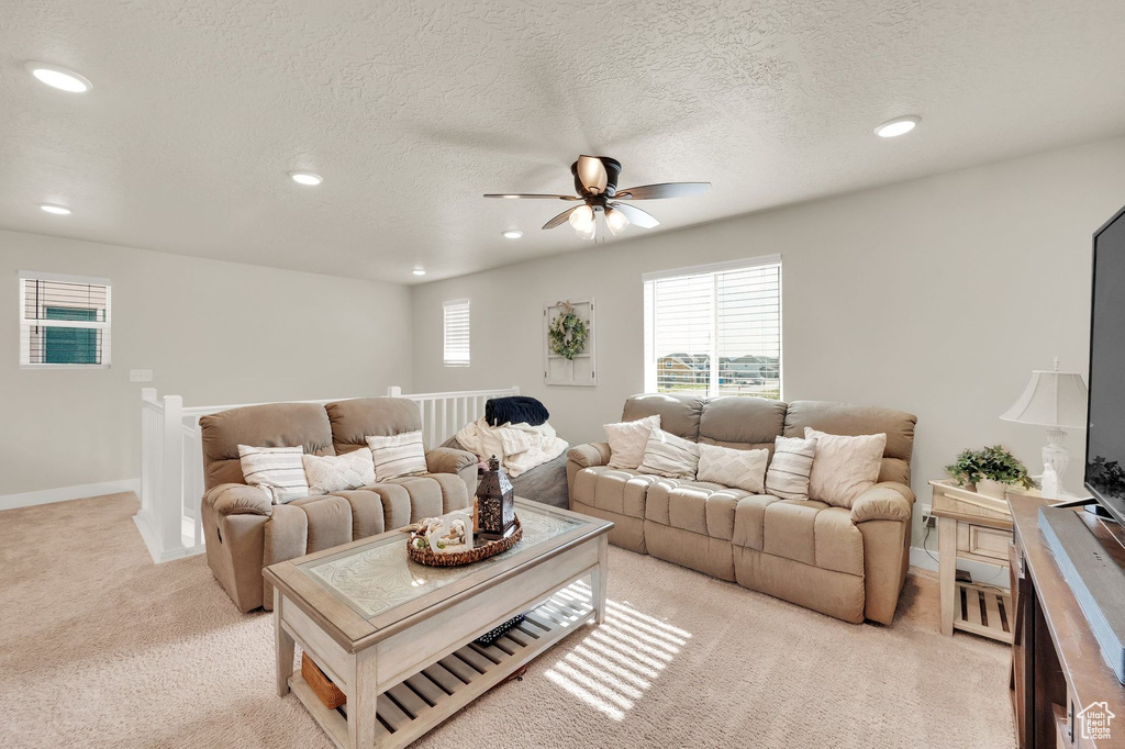 Living room with light carpet, a ceiling fan, recessed lighting, healthy amount of natural light, and baseboards