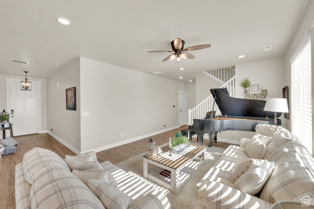 Living room featuring stairs, wood finished floors, a ceiling fan, recessed lighting, and baseboards