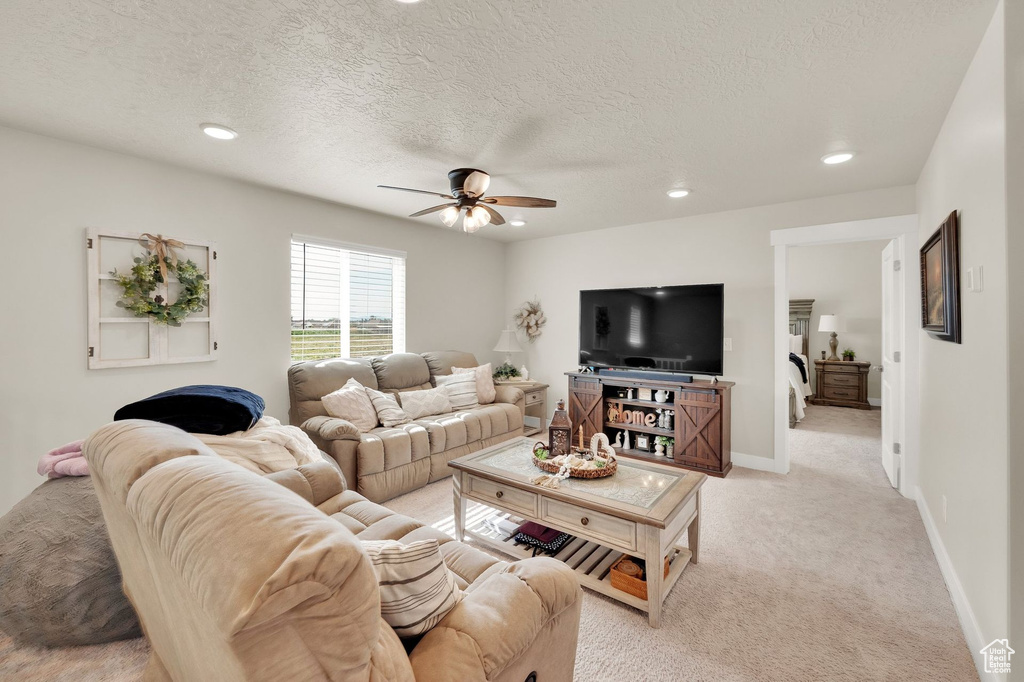Living area with a ceiling fan, recessed lighting, light colored carpet, a textured ceiling, and baseboards
