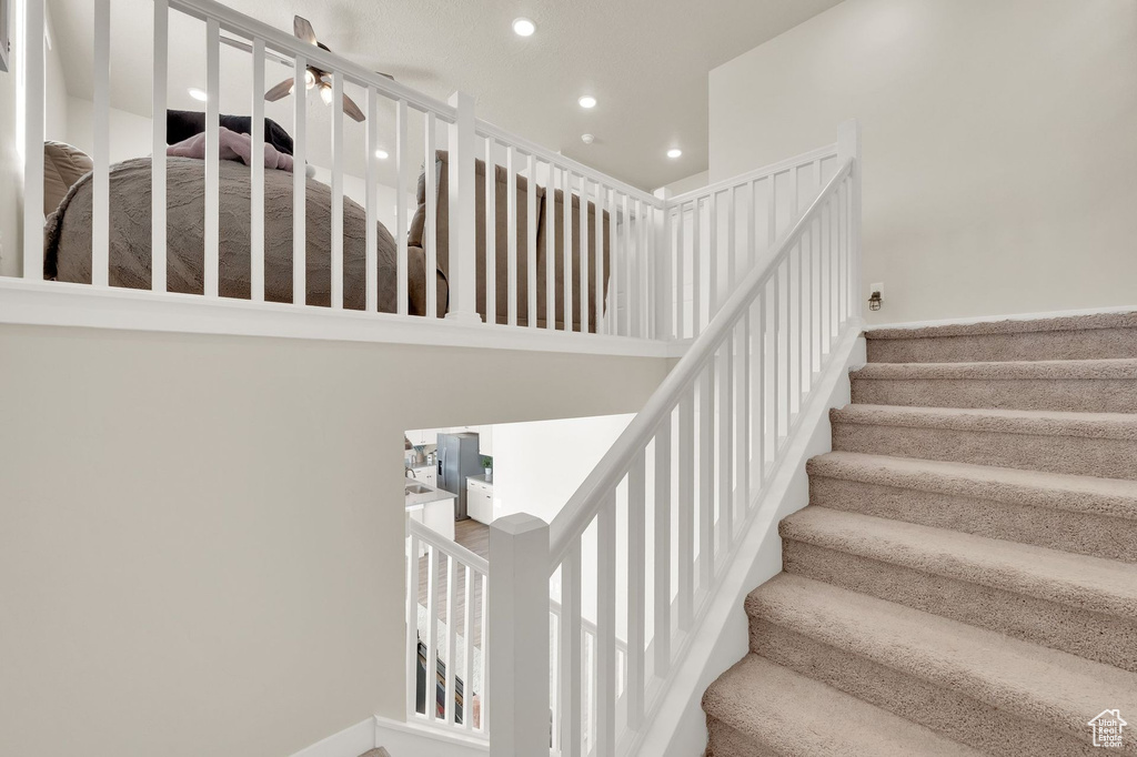Staircase with recessed lighting and a ceiling fan