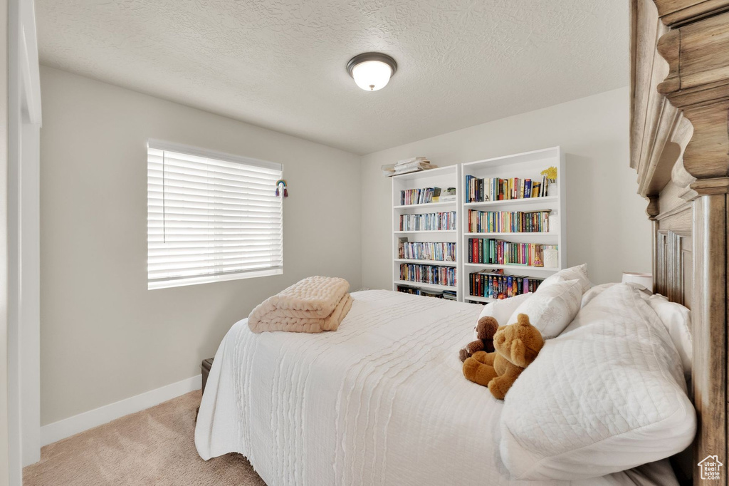 Bedroom with light carpet, baseboards, and a textured ceiling