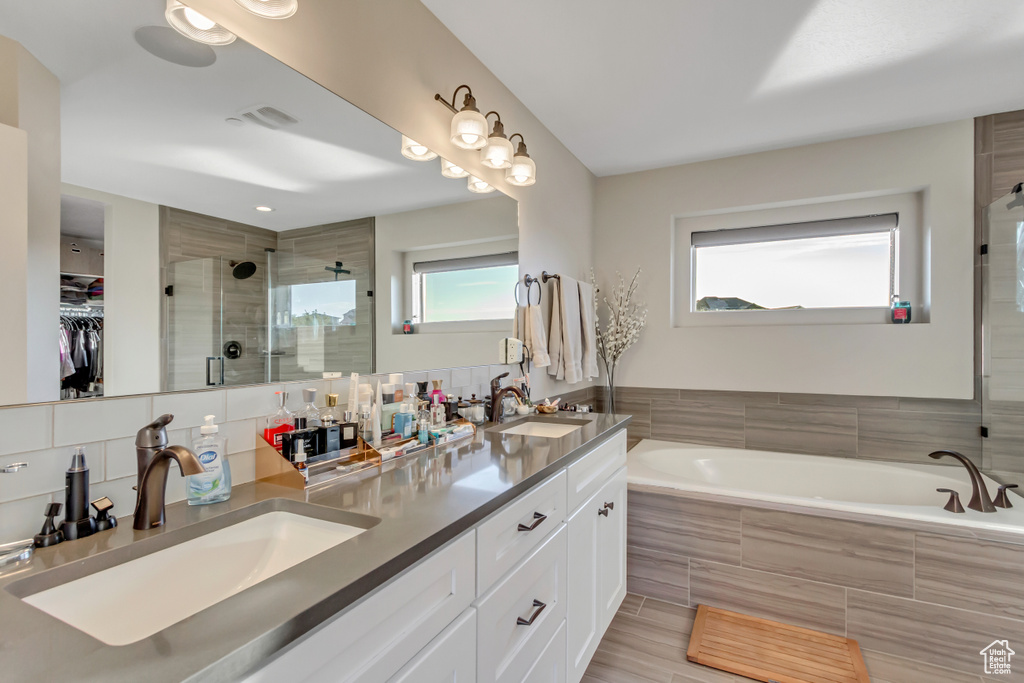 Bathroom featuring a stall shower, double vanity, a bath, and a walk in closet
