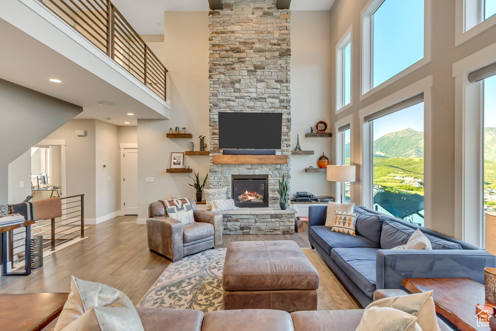 Living area featuring a high ceiling, wood finished floors, plenty of natural light, a fireplace, and baseboards