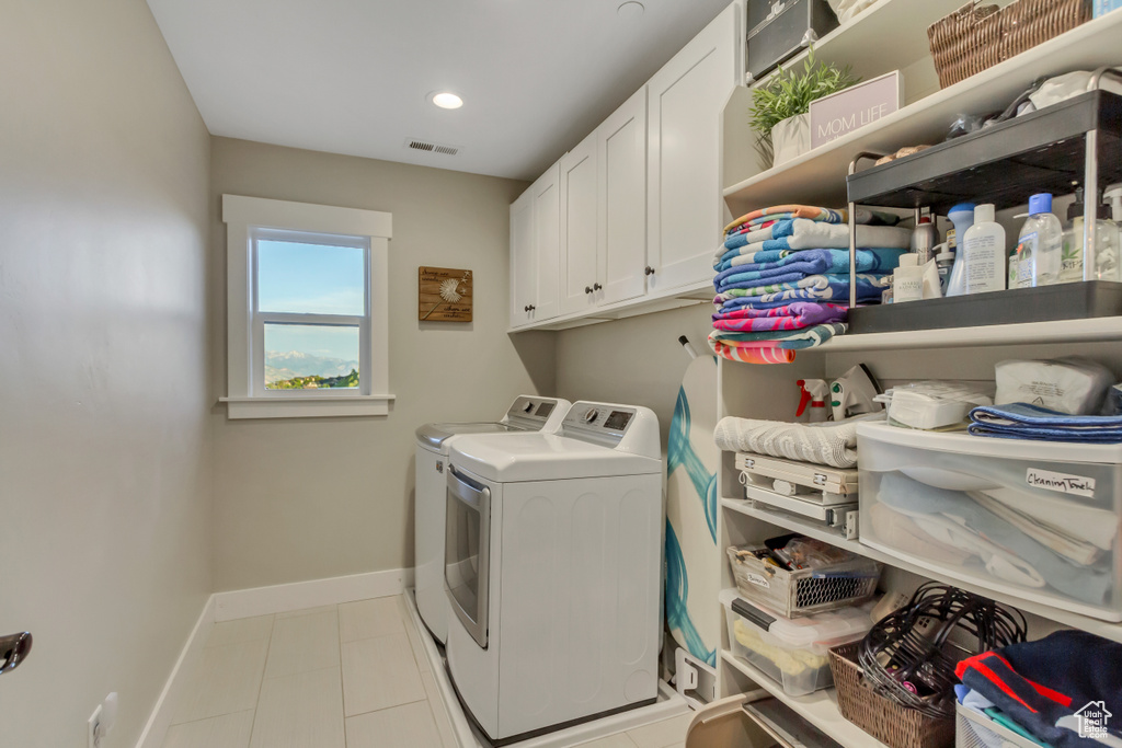 Laundry area featuring cabinet space, washer and dryer, baseboards, light tile patterned floors, and recessed lighting