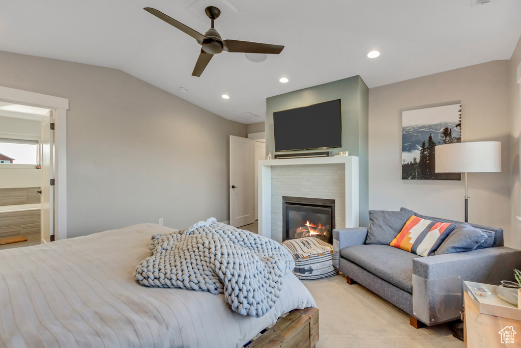 Bedroom featuring a glass covered fireplace, lofted ceiling, recessed lighting, ceiling fan, and ensuite bathroom