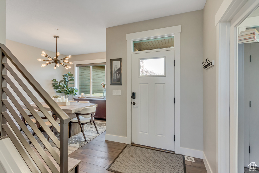 Entrance foyer with wood finished floors, a chandelier, and baseboards