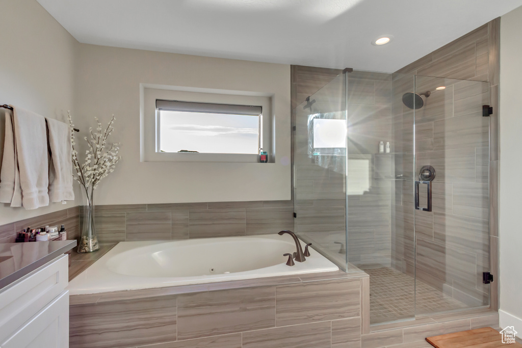 Bathroom featuring a bath, a stall shower, recessed lighting, and vanity