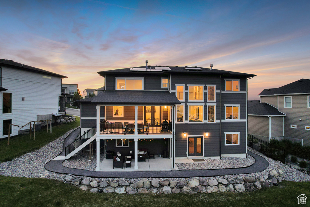 Rear view of property featuring a patio, roof mounted solar panels, and stairs