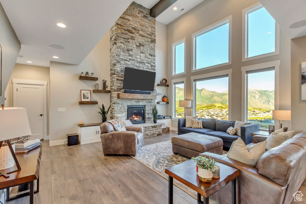 Living room featuring light wood-style floors, a towering ceiling, a fireplace, recessed lighting, and baseboards