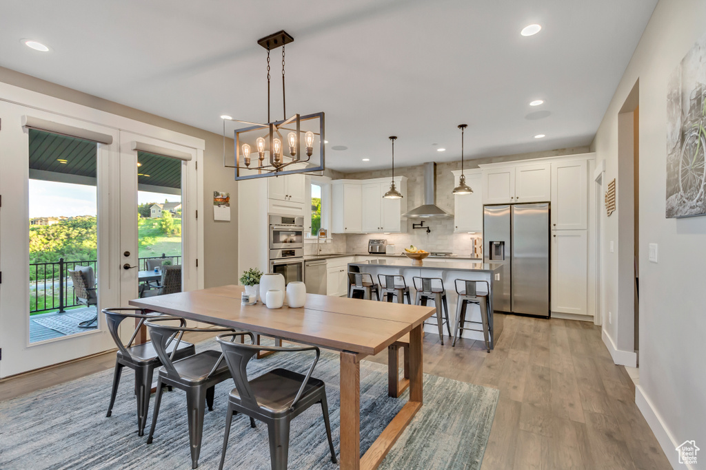 Dining room with light wood-type flooring, recessed lighting, baseboards, a chandelier, and french doors