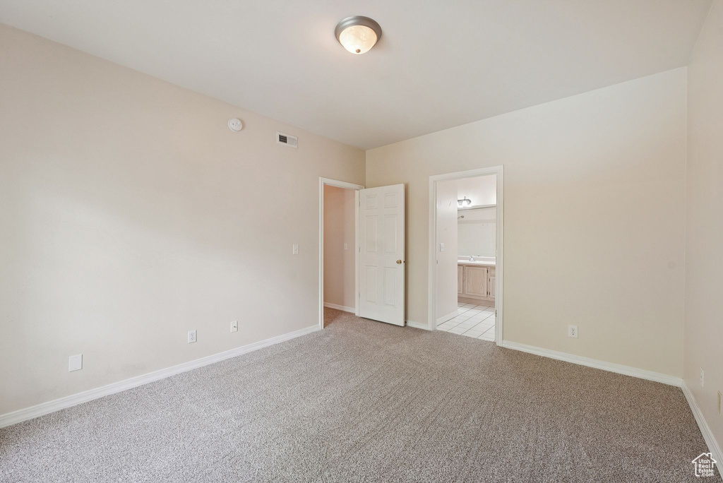 Empty room featuring light carpet, baseboards, and a smoke detector