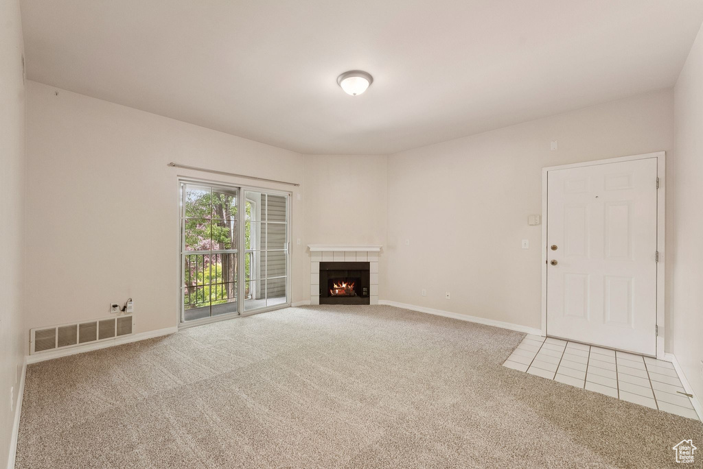 Unfurnished living room featuring carpet flooring, a fireplace, baseboards, and tile patterned floors