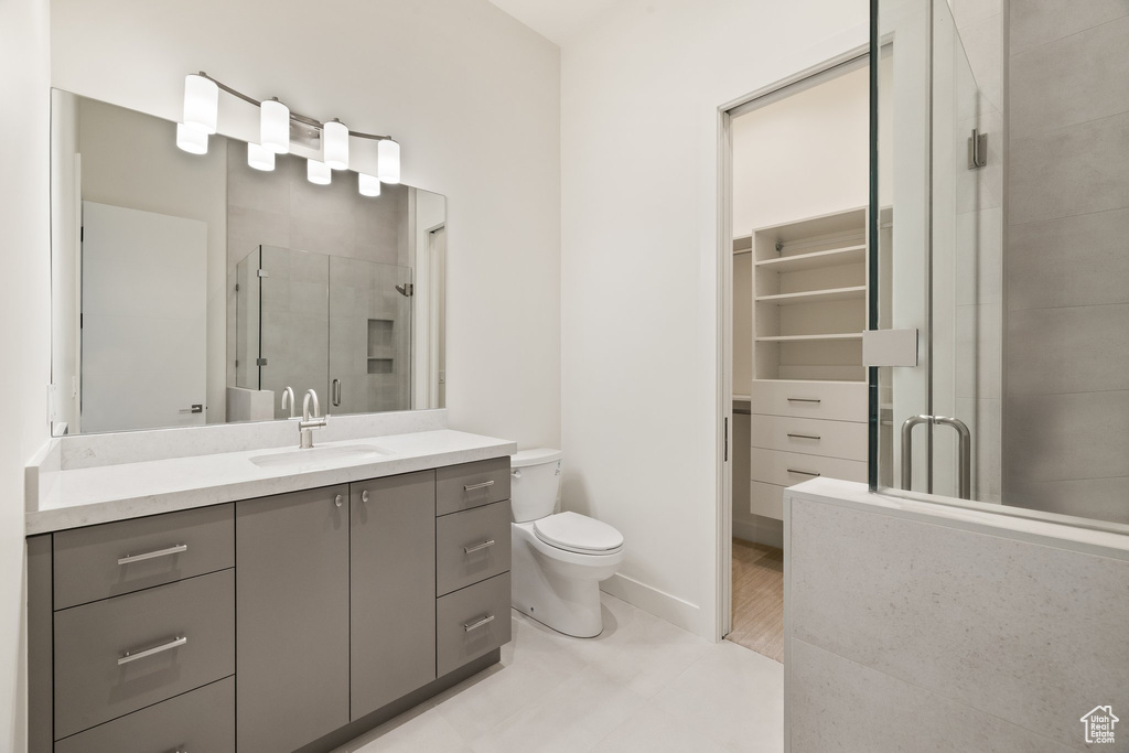 Full bathroom with toilet, vanity, a stall shower, and baseboards