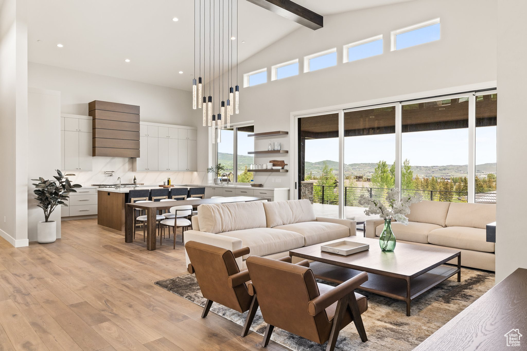 Living area featuring high vaulted ceiling, beam ceiling, light wood-style flooring, and recessed lighting