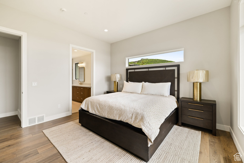 Bedroom featuring baseboards, wood finished floors, ensuite bath, and recessed lighting