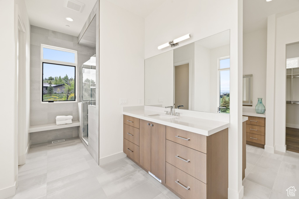 Bathroom with vanity, plenty of natural light, baseboards, and a shower stall