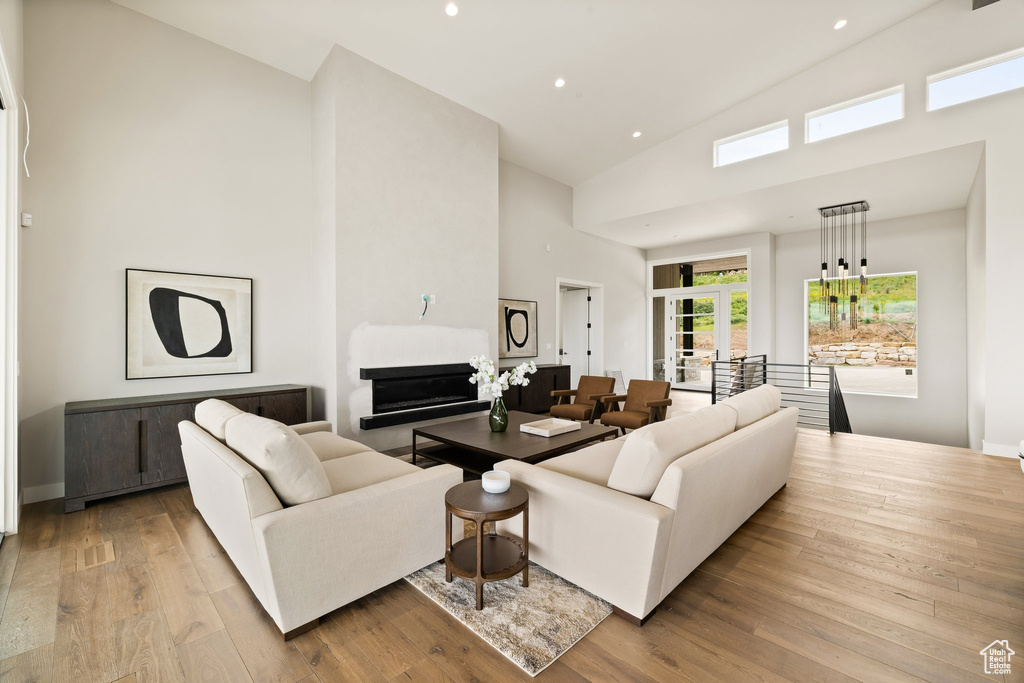 Living room with high vaulted ceiling, hardwood / wood-style floors, recessed lighting, french doors, and baseboards