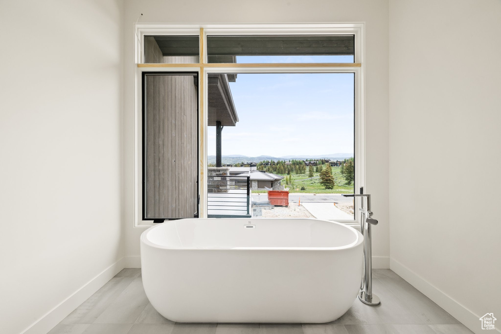 Full bathroom featuring baseboards, a soaking tub, and a mountain view