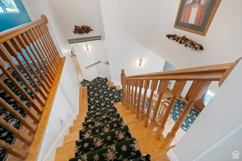 Stairway with a high ceiling, baseboards, and wood finished floors