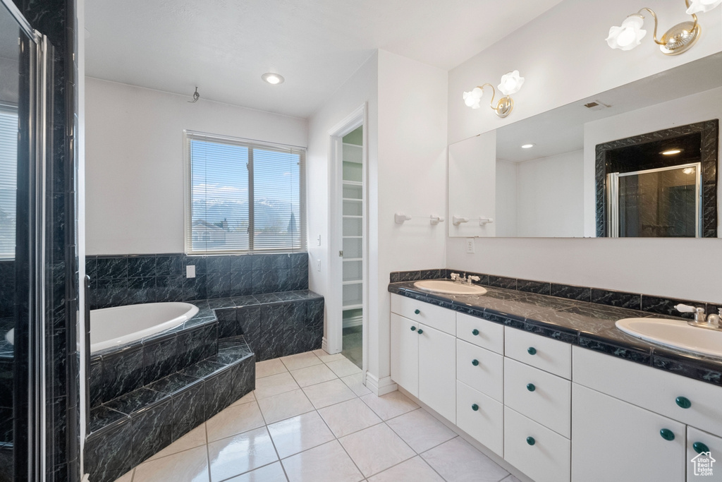 Full bath featuring a garden tub, a stall shower, double vanity, tile patterned floors, and a spacious closet