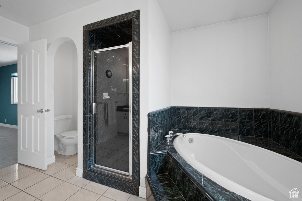 Bathroom with toilet, a garden tub, a shower stall, and tile patterned flooring