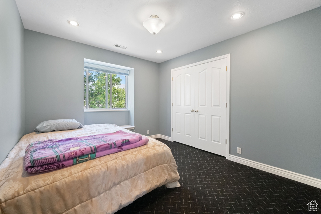 Bedroom with dark colored carpet, recessed lighting, baseboards, and a closet