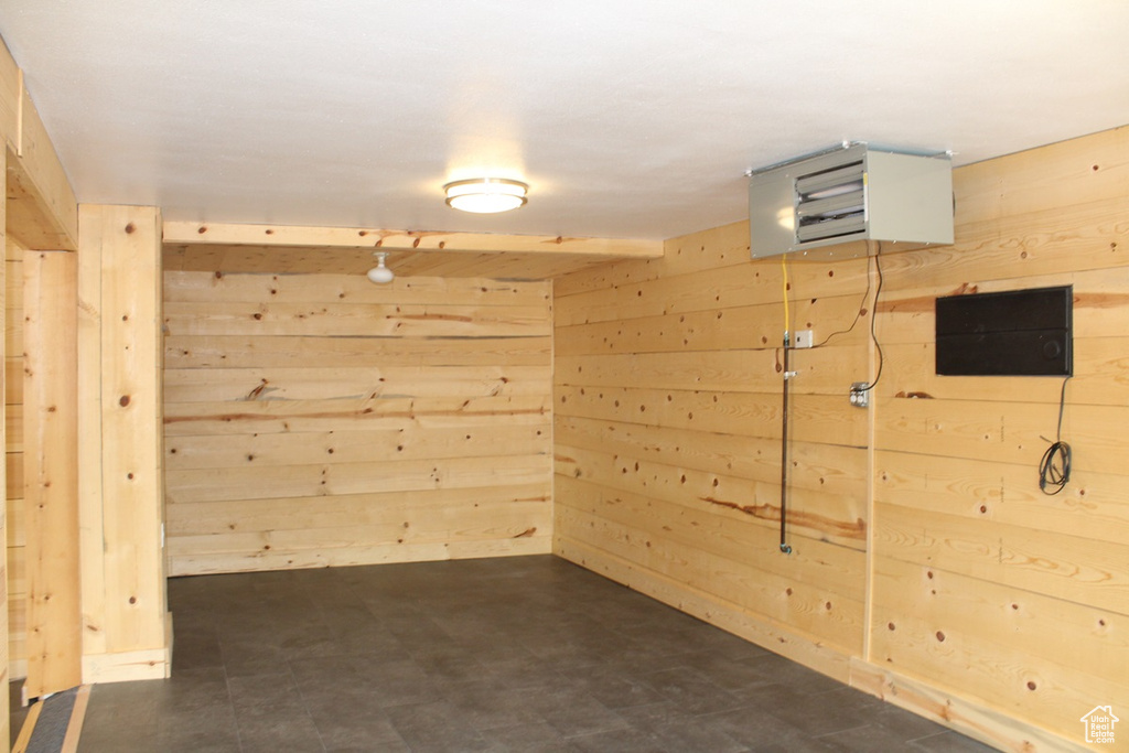 Empty room with wood walls, dark floors, and a heating unit