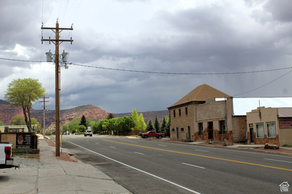 View of asphalt road featuring a mountain view, sidewalks, and curbs