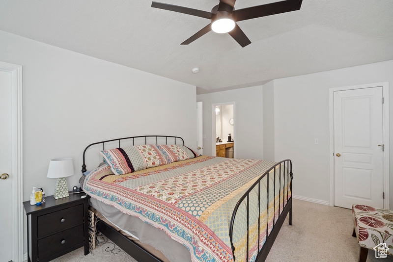 Bedroom featuring light carpet, baseboards, connected bathroom, and ceiling fan