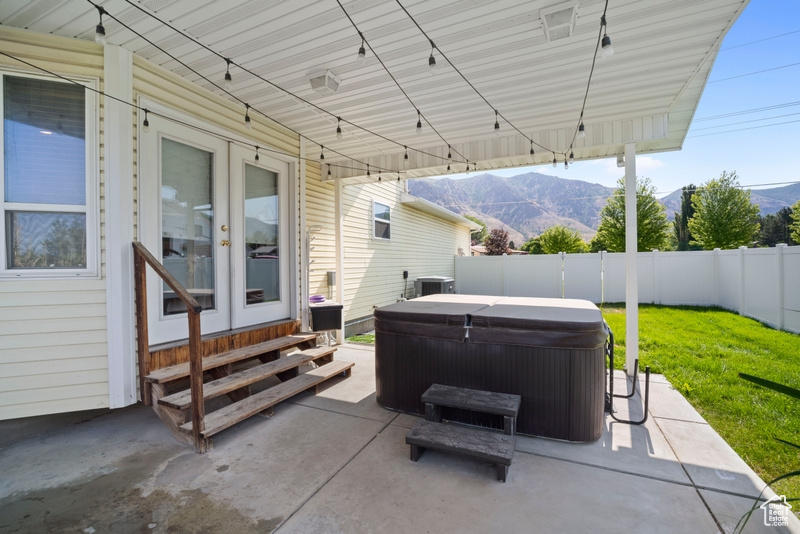 Fenced backyard featuring a hot tub, french doors, a mountain view, entry steps, and a patio