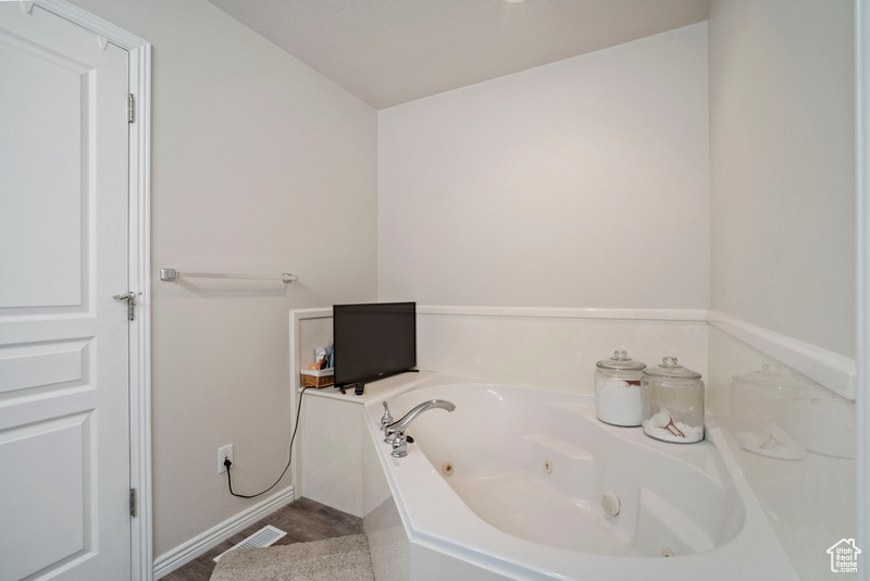 Bathroom featuring a tub with jets and baseboards