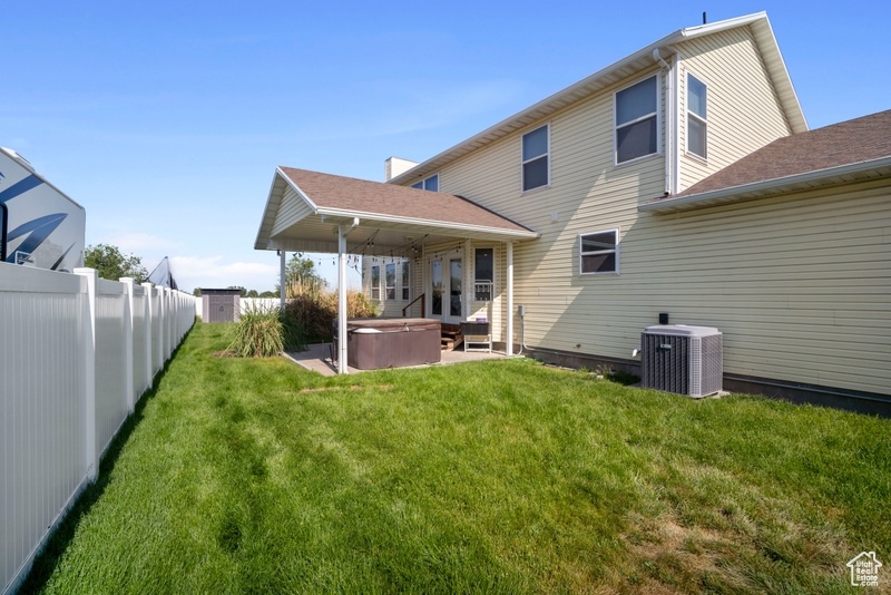 Rear view of house with a hot tub, central air condition unit, and a patio area