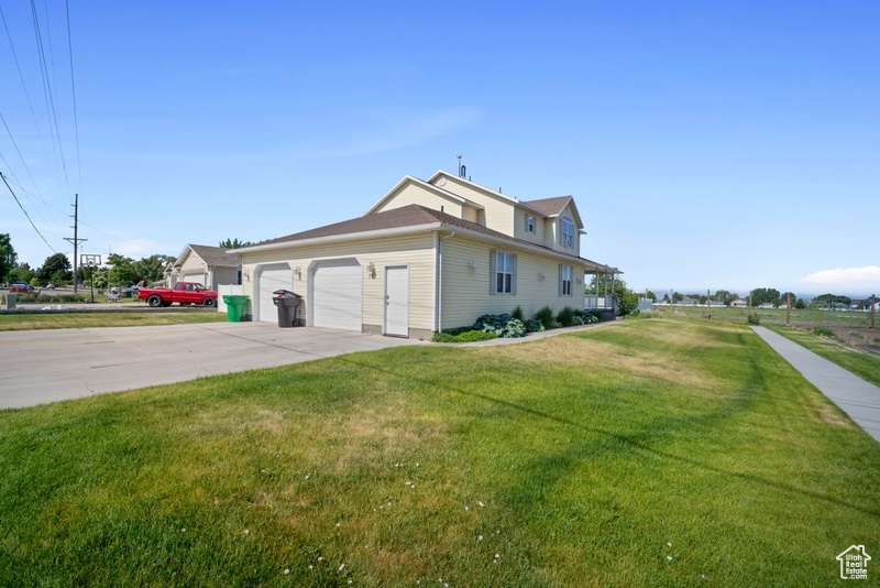 View of home\'s exterior featuring a lawn, an attached garage, and concrete driveway