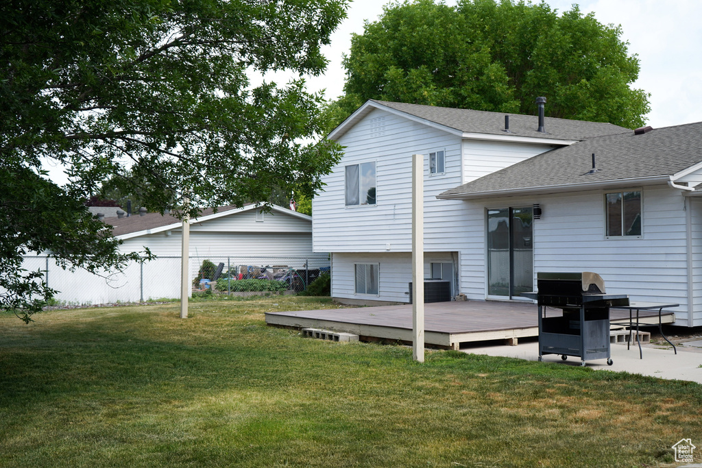Rear view of house with a wooden deck, roof with shingles, and cooling unit