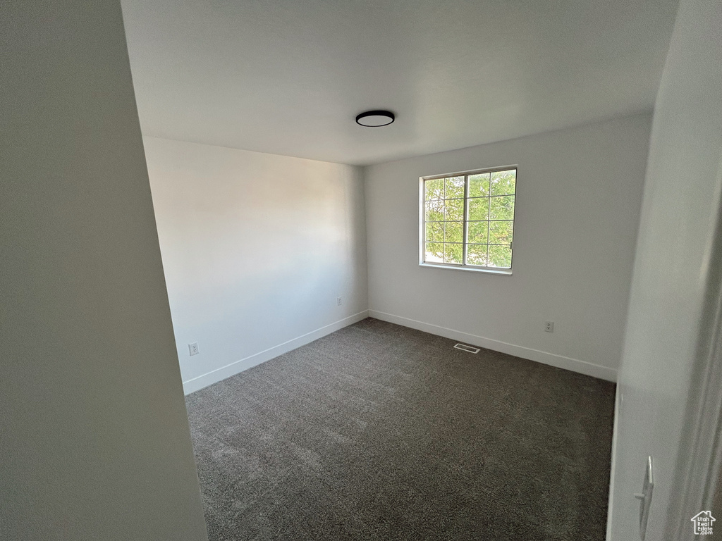 Empty room with dark colored carpet and baseboards