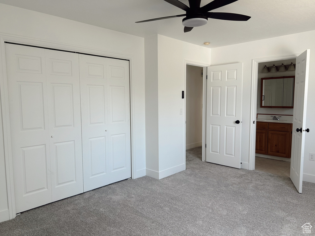 Unfurnished bedroom featuring light carpet, a closet, baseboards, ensuite bathroom, and a ceiling fan