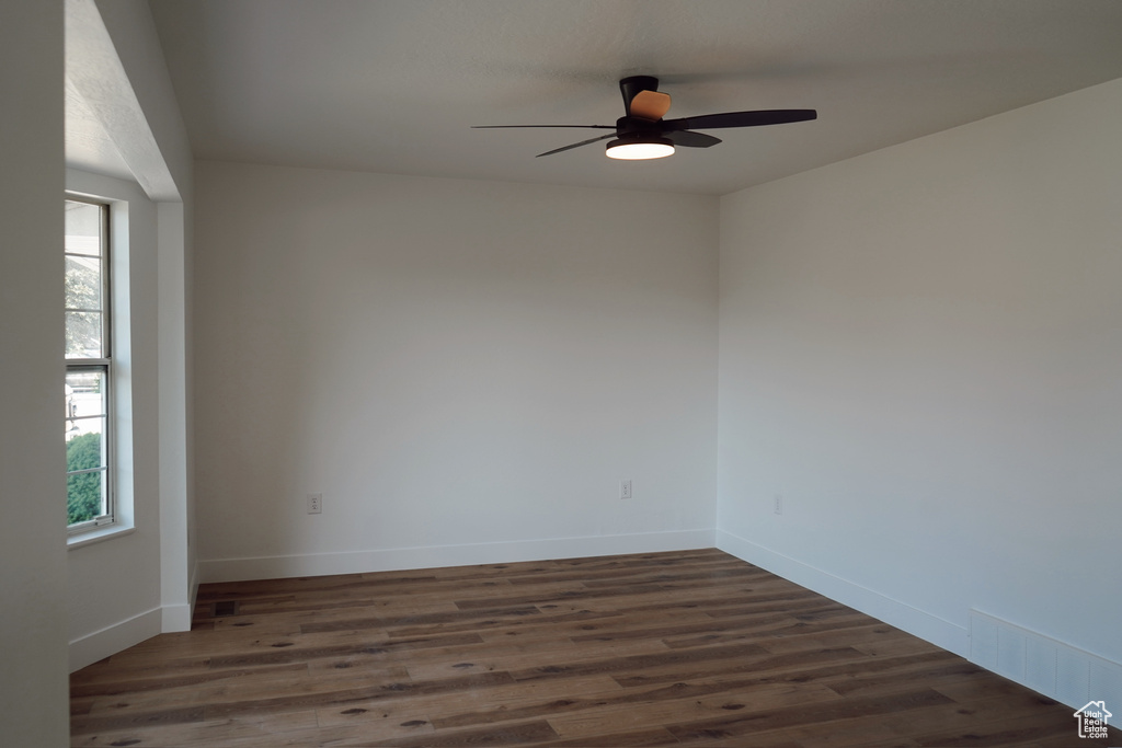 Spare room featuring a ceiling fan, dark wood finished floors, and baseboards