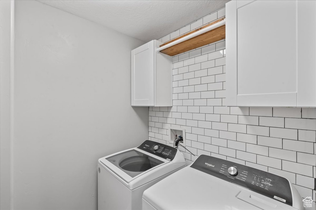 Washroom with cabinet space, washing machine and dryer, and a textured ceiling