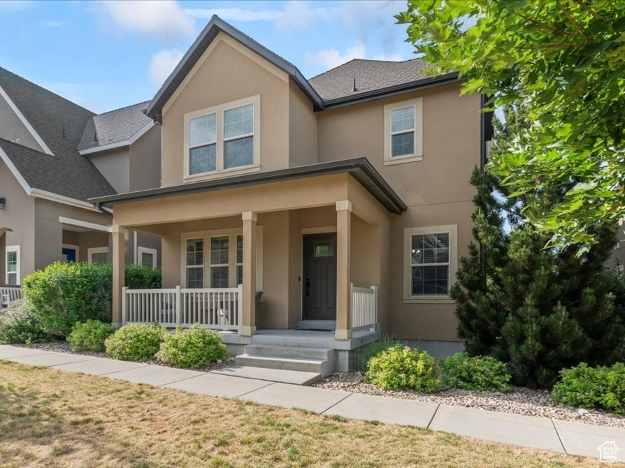 View of front facade featuring stucco siding, a porch, and a front yard