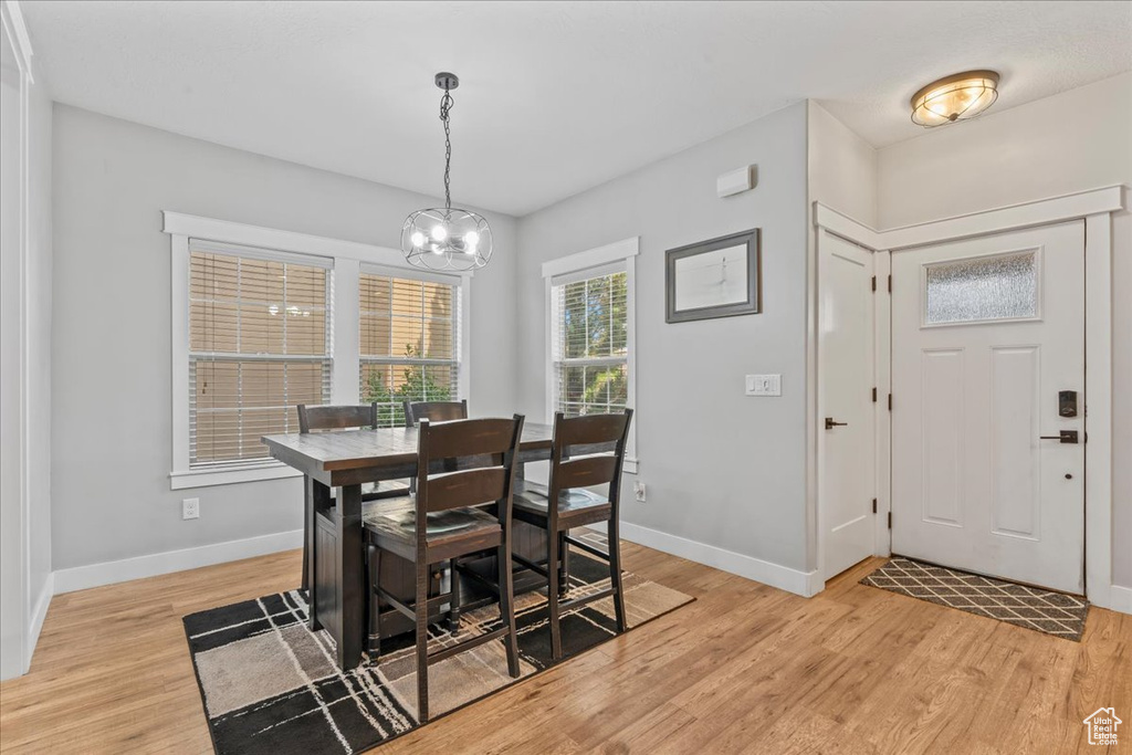 Dining area featuring light wood-type flooring, a chandelier, and baseboards