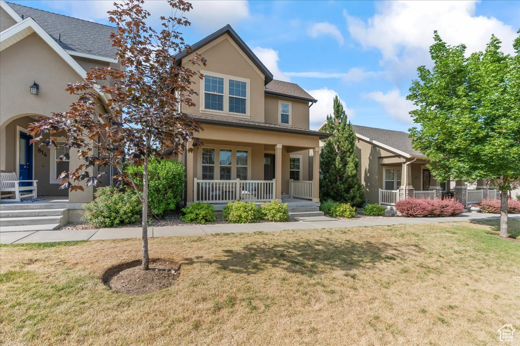 View of front of property featuring a porch, stucco siding, and a front yard