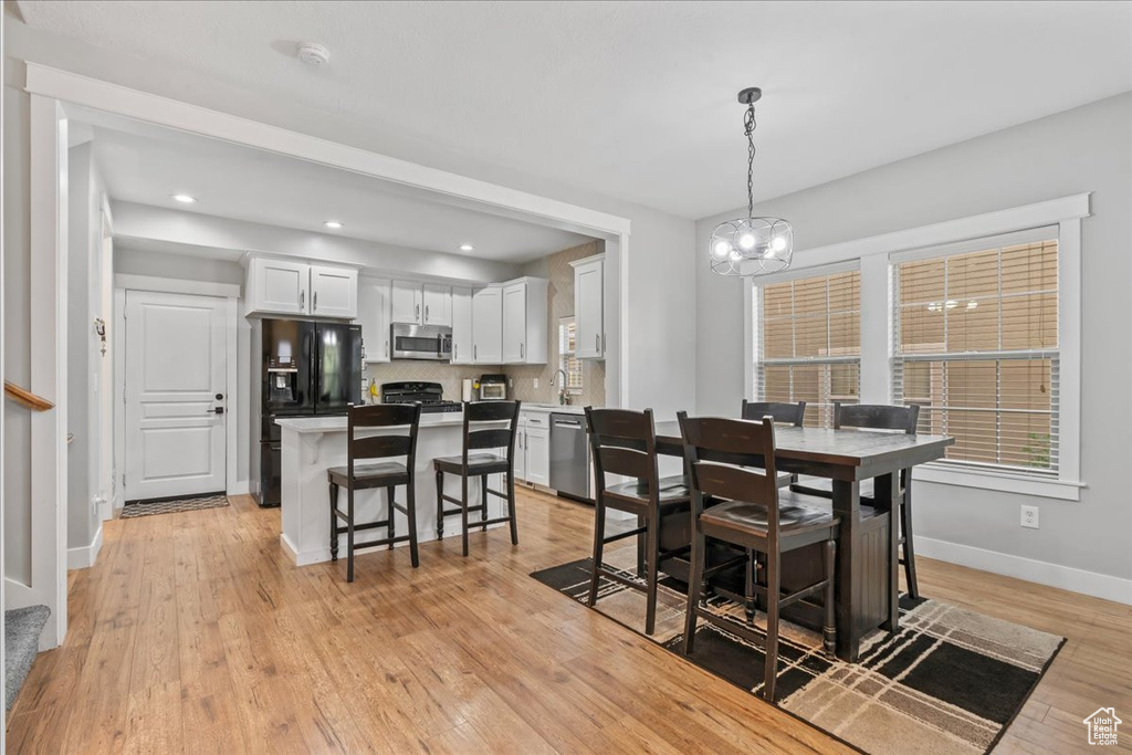 Dining room featuring a chandelier, light wood-style floors, baseboards, and recessed lighting