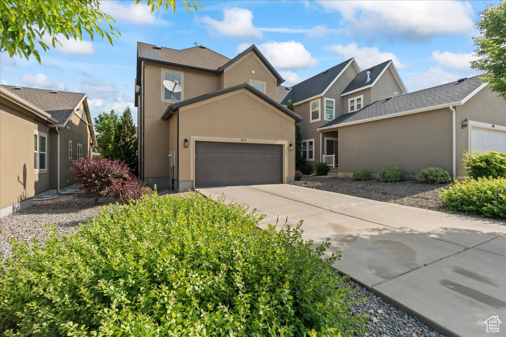 Traditional home with an attached garage, concrete driveway, and stucco siding