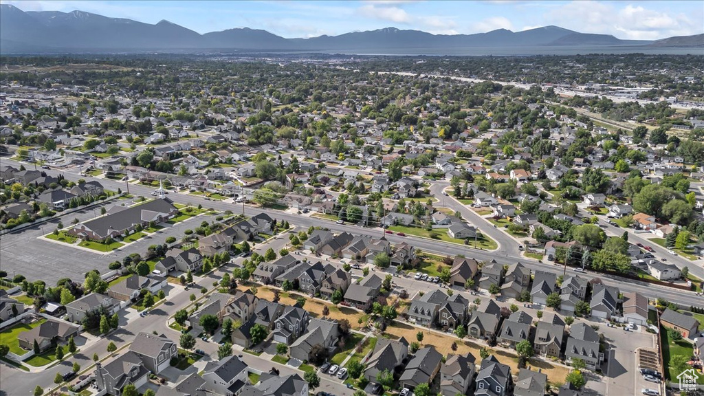 Aerial view of property and surrounding area featuring a mountainous background and nearby suburban area
